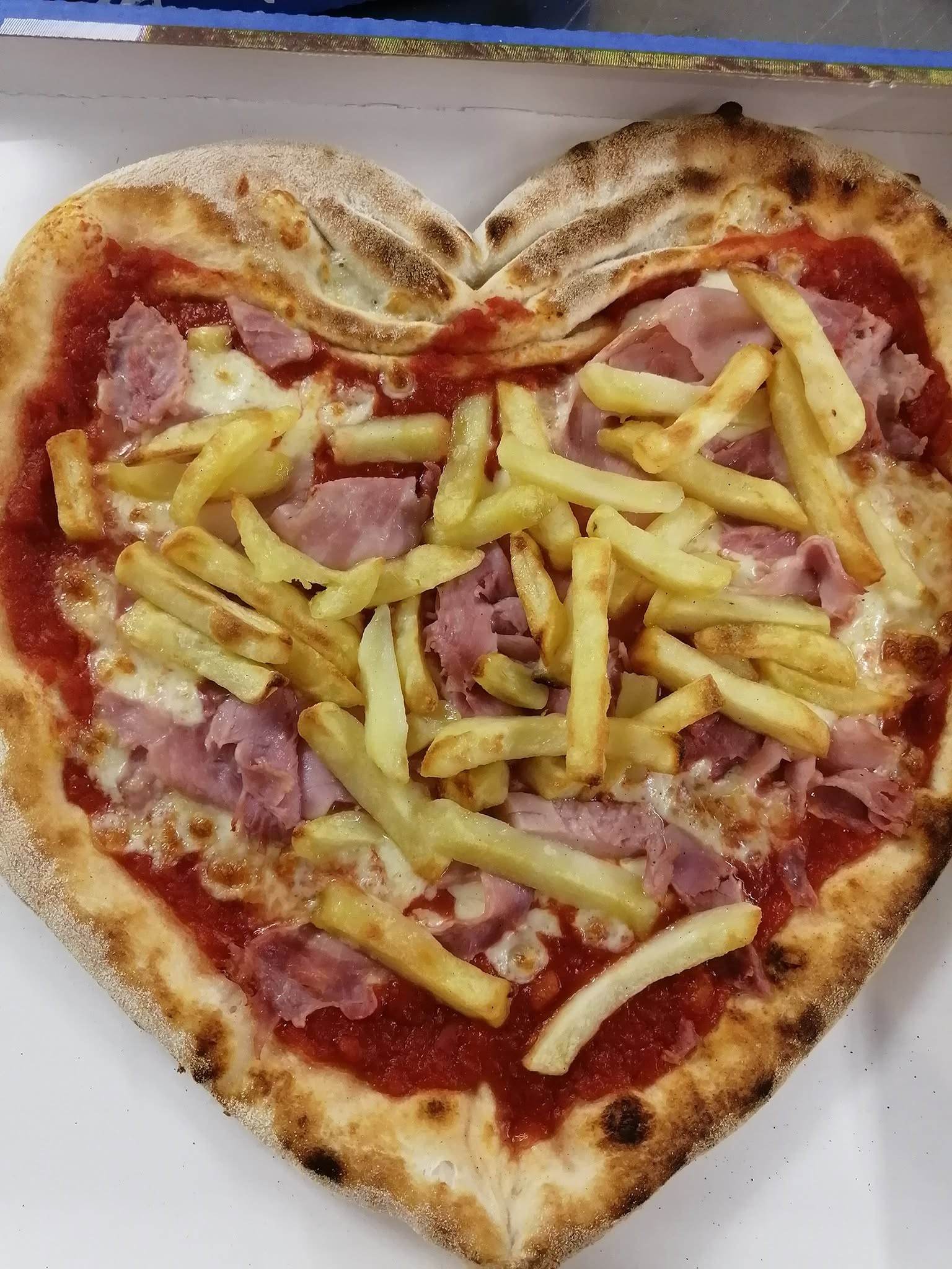 Pizza stesa a forma di cuore con pomodoro, mozzarella, prosciutto cotto e patatine fritte dorate