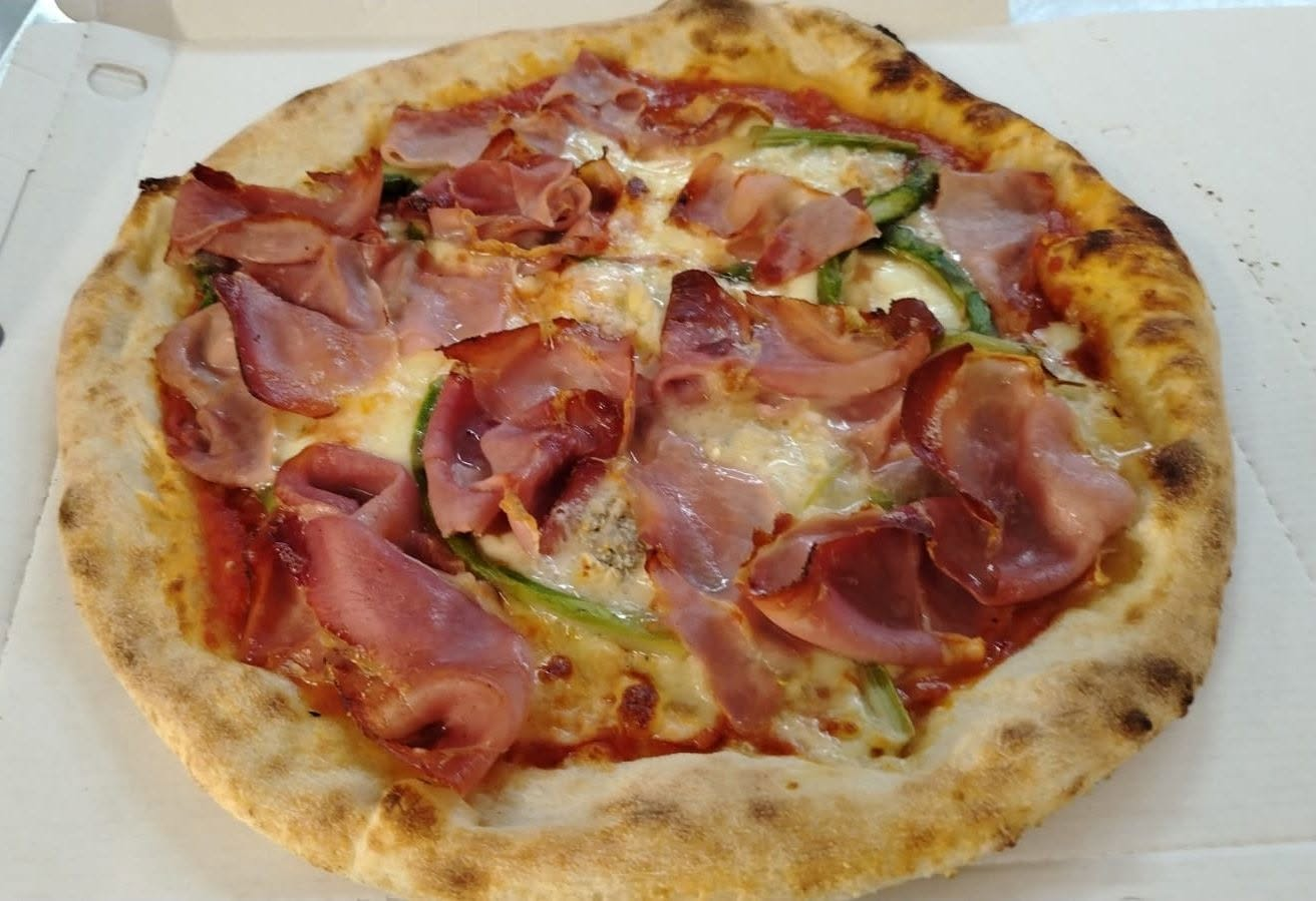 Pizza con fette di speck nostrano arrostito, zucchine e mozzarella fusa